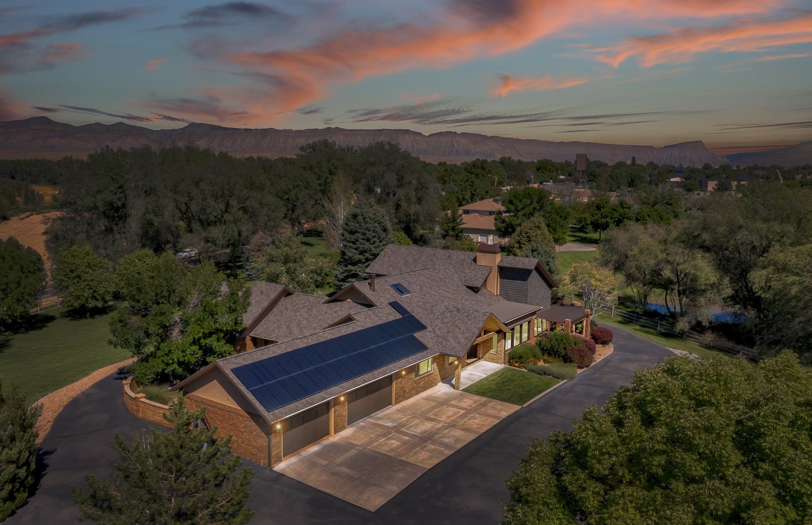 Welcome to 2625 H Road, an exquisite Grand Junction estate where history and charm seamlessly blend to craft an extraordinary home. Formerly known as the Suplizio House, this stunning property spans 4.5 acres and encompasses over 6000 square feet of living space across the main home and ADU. With a 2-car attached garage and a 2000 square foot detached temperature-controlled shop featuring an exercise room, this estate caters to both luxury and functionality. Immerse yourself in the outdoor oasis that includes a dedicated irrigation pond, custom play-set, lush landscaping, trees, and garden areas. Multiple delightful patios invite you to unwind and soak in the tranquility of your surroundings. Meticulously maintained and updated over the years, this immaculate home boasts 4 bedrooms, each with an attached ensuite. The primary bedroom showcases an impressive closet, a private fireplace, and a deck offering panoramic views of Mount Garfield and the Mesa. A dedicated office and guest bathroom are strategically placed behind the bar area and game room, fostering a perfect balance of work and play. A dual fireplace connecting the game room and living room creates warmth and unity between the spaces. The chef's kitchen, featuring a 48-inch Thermador Gas Range and Subzero Refrigerator, is a culinary haven. The downstairs theatre room with a private bathroom provides an amazing retreat for relaxation.Transitional and timeless finishes grace every corner of this home, from the imported travertine tile from Turkey to the bar top with a story originating from a bar near Wrigley Field in Chicago. Recent upgrades include a new roof and gutters for the home, shop, and ADU, along with owned solar to enhance energy efficiency. Decorative shake siding adds character, complementing the original brick and newer stucco work. Cathedral ceilings welcome you into the bright and airy spaces, enhanced by fresh paint and stained beams highlighting the home's architectural lines. New decorative lighting throughout updates the aesthetic of each living space. The addition of a mudroom off the attached garage provides extra storage and convenience, while a mini-split in the ADU ensures a comfortable space for guests or a home office. Attached to the ADU, discover a charming greenhouse with access to garden areas, completing the picture of comfortable living in a serene setting. This home is not just a residence; it's a piece of Grand Junction history, waiting for you to make it yours.