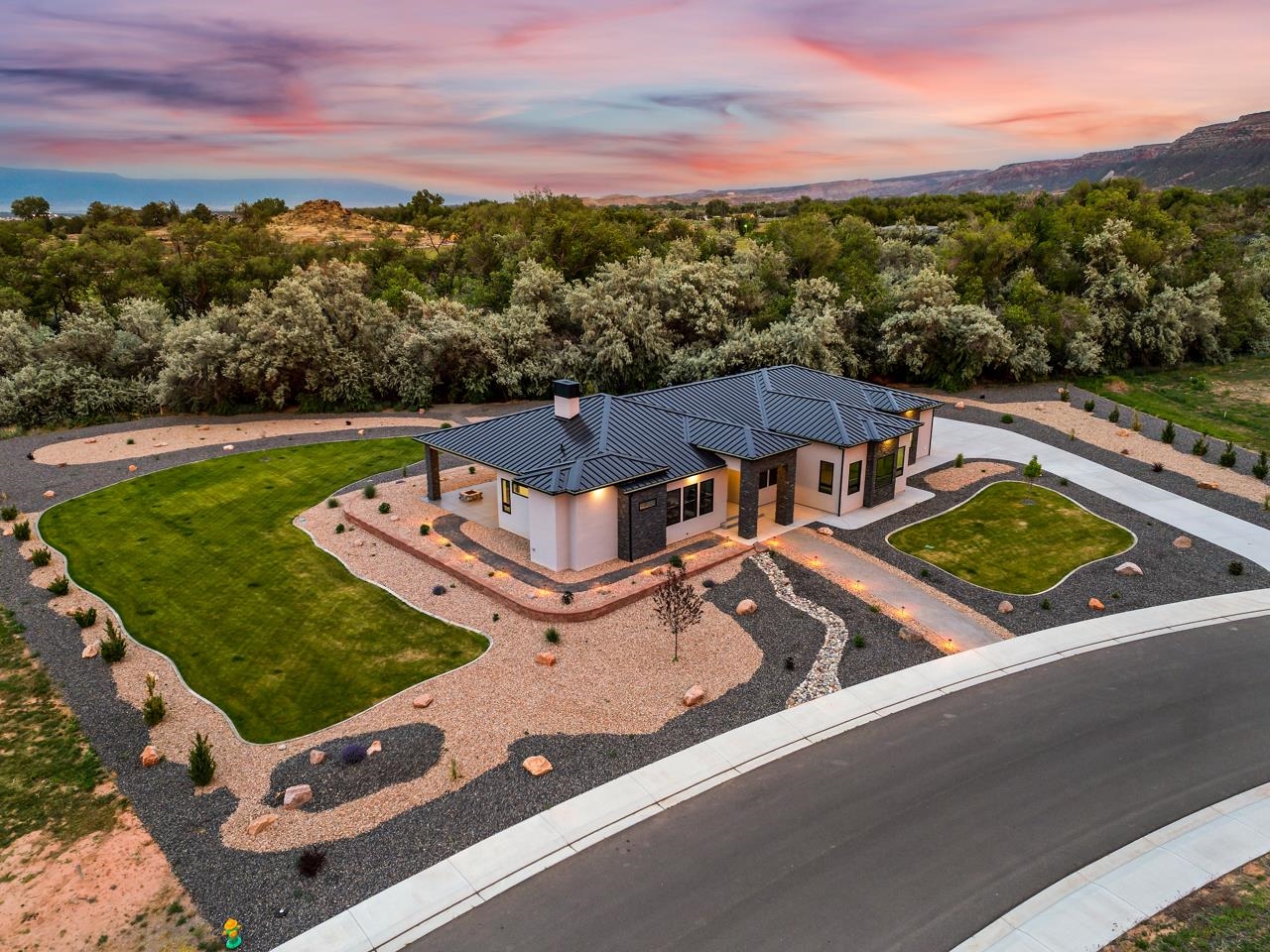 This modern dream home is nestled in the Redlands area of Grand Junction, a masterpiece of contemporary design & luxury living. Completed in May of 2023, this home boasts impeccable landscaping & striking architectural features, blending seamlessly with the stunning Western Colorado landscape. As you step inside, you'll be greeted by the elegance of durable Luxury Vinyl Plank flooring throughout, setting the stage for the open living space characterized by soaring ceilings & floor-to-ceiling windows framing panoramic views of the backyard, open space, & Bookcliff vistas. Cozy up by the tile fireplace in the living room, enjoying the ambiance of a sleek modern gas fire. The kitchen is a culinary haven, featuring granite countertops, black & gold textured backsplash, stainless appliances, floor to ceiling cabinetry, & a walk-in pantry. The adjacent dining area and breakfast bar island offer ample space for entertaining guests. Indulge in entertainment in the theater room, complete with stepped seating & surround sound. Retreat to the spacious guest room with its own ¾ 4-piece en suite bath & walk-in closet, while the luxurious primary suite boasts a sophisticated closet system, sauna, & a lavish ¾ 4-piece en suite bath & access to the laundry room. Additional highlights include a home office with built-in desk, a home gym with breathtaking views of the Colorado National Monument & Independence Rock, & a full bath for guests. Enjoy the convenience & peace of mind provided by the whole-home sound system, electric shades, smart lights, security system, central vacuum, & programmable thermostats. The attached oversized 3-car garage offers built-in storage & ample space for parking & projects as well as a separate storage room. Relax on the large covered back patio overlooking the expertly landscaped terraced yard with a small waterfall, wooded open space, & captivating views of the Bookcliff mountains. The Soaring Eagle Community offers a serene lifestyle surrounded by red cliffs & desert wildlife. With proximity to golf courses, hiking & biking trails, parks, schools, shopping, & dining options, this is more than just a home—it's a gateway to the best of the Grand Valley. Community amenities will include a clubhouse with pickleball court, patios, ponds, & space for residents to relax together. Come experience luxury living at its finest in this remarkable modern retreat.