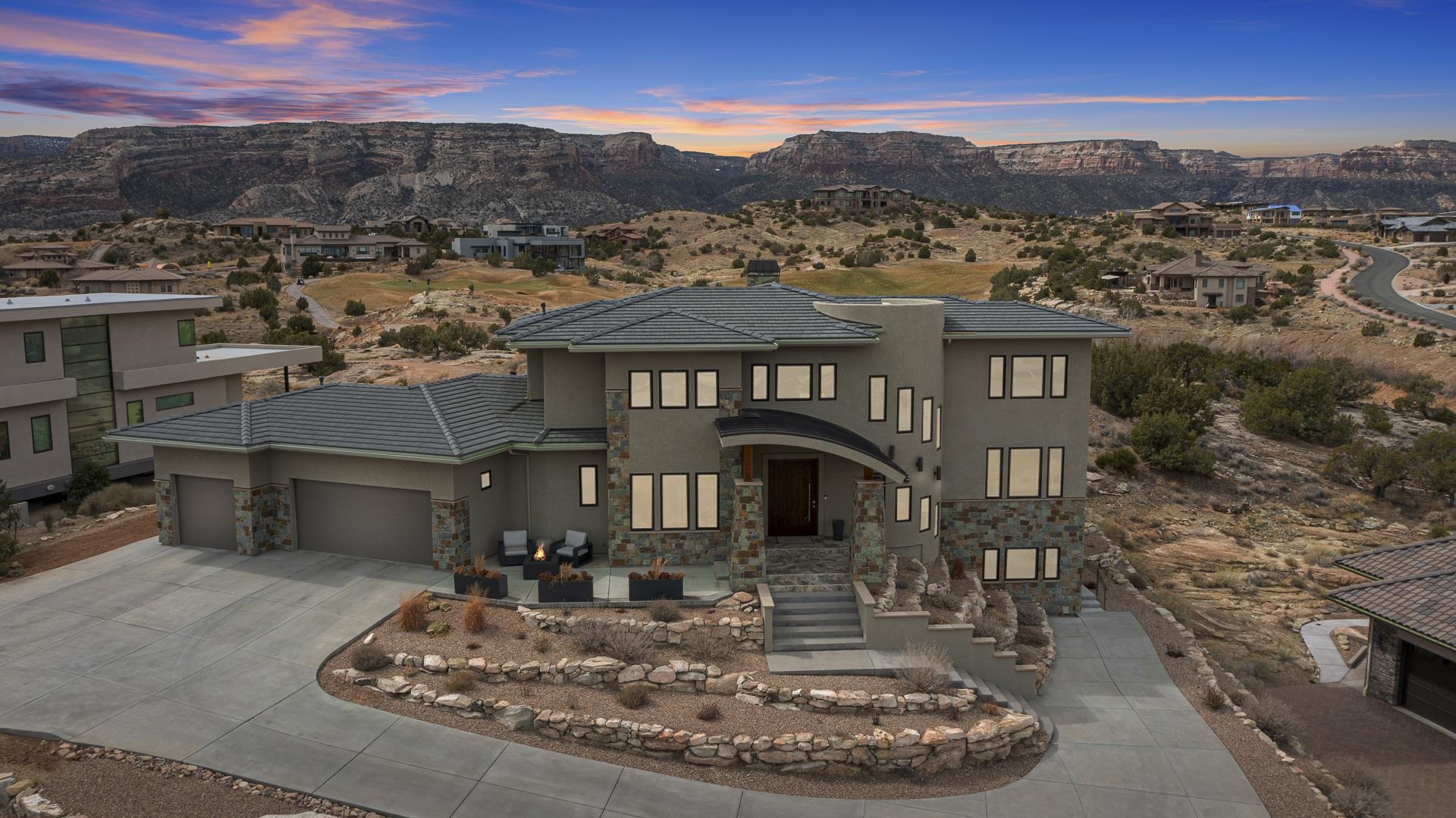 In Grand Junction's premier living environment, at the top of the prestigious Redlands Mesa Golf Community, with 360-degree views of stunning Bookcliffs, Colorado National Monument, and the twinkling city lights, this luxurious 5 BR, 4 1/2 BTH home offers the ultimate in quality, convenience and Western Colorado lifestyle! Built around a spectacular great room, open dining area, and gourmet kitchen, This modern home has it all. Private master suite, spacious covered outdoor living space, multi-generational guest suite,  heated driveway, and 3-car garage. The quality is in the details: Wolf Range, Bosch appliances, 2 dishwashers, secret butler's pantry. High-end light fixtures and ceiling fans, a smart home audio system, flat-mount art framed TVs throughout, jaw-dropping custom chandelier, private backyard entertaining, relaxing fire and water features, an outdoor OLED TV, grilling space, remote-controlled sunshade. Separate entrance to the guest suite. Epoxy-coated garage floor, EV charging outlet, heated driveway with auto moisture sensor. Tons of storage and too many features and amenities to mention here. A must-see if you love quality, views, and miles of hiking and biking trails out your front door.