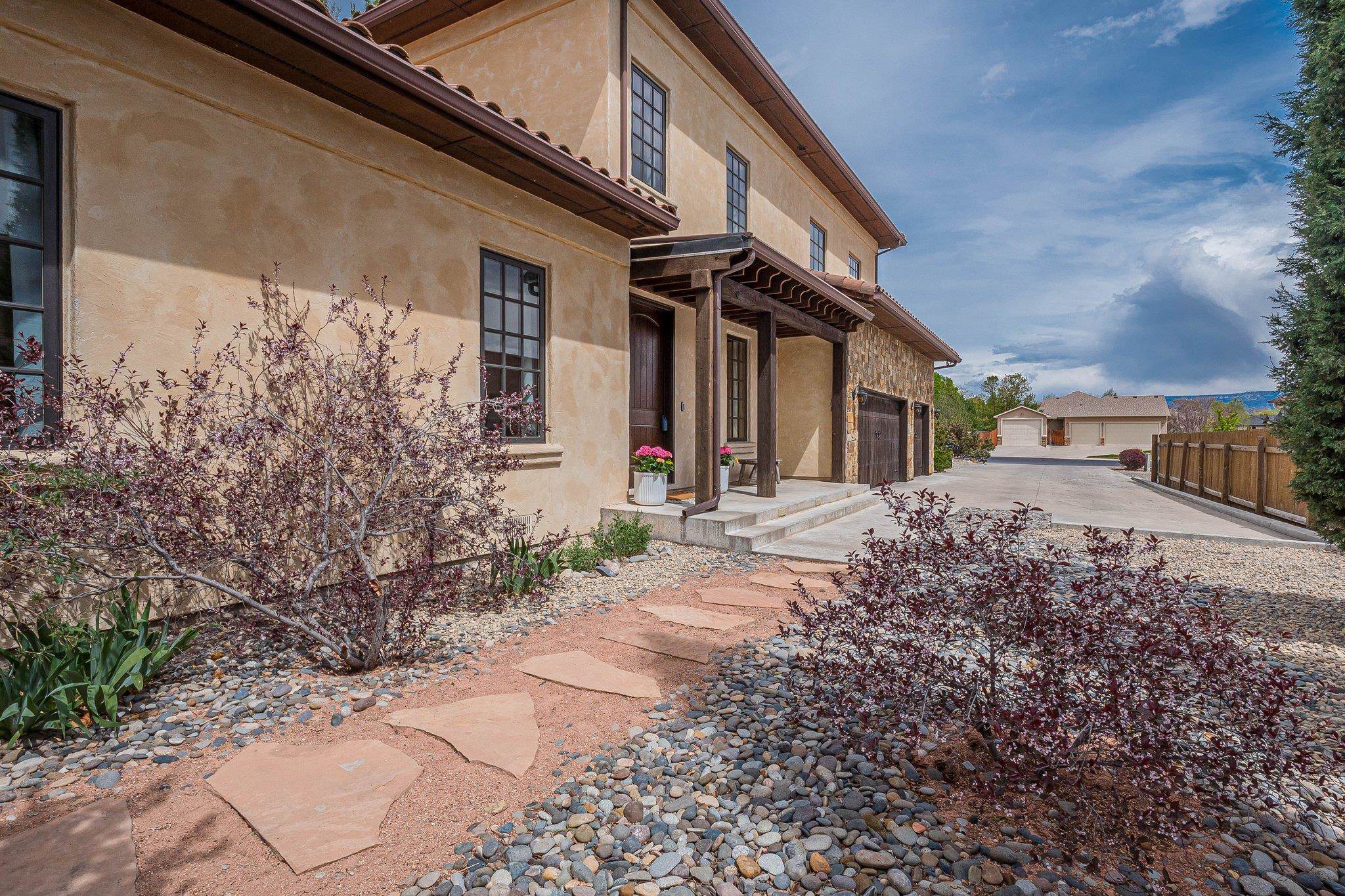 Welcome to your new dream home in the north area of Grand Junction, Colorado! The great views surround you as you are able to see the Grand Mesa, the Bookcliffs, & the Colorado National Monument. You are not far from shopping, only minutes away from town, & close to hiking spots, making for easy access to local amenities & recreation. While town is never too far away, enjoy the privacy & peace of the location. Upon entering, you're greeted by the hardwood flooring & vaulted ceilings adorned with exquisite wood finishes. Natural light pours into the informal dining area, creating a welcoming atmosphere complemented by a hanging light fixture & a wood-accented ceiling. The spacious living area has a stone/brick gas fireplace, a unique ceiling fan, & surround sound, perfect for cozy relaxation or entertaining. Step into the impeccable kitchen featuring solid stone countertops, wood & glass cabinets, & a brick alcove surrounding the gas range, adding a touch of character to meal preparation. Adjacent to the kitchen, is a breakfast nook with large windows & a sit-up counter which provides a delightful space for casual dining.  The main level also hosts four generously sized bedrooms, each with its own distinctive features, along with a shared four-piece bathroom featuring dual sinks & stone countertops. Venture upstairs to discover a versatile space ideal for a home office or additional living area, complete with a convenient half bathroom & a beautiful window transom. Another expansive room awaits, offering endless possibilities for use, with access to a balcony overlooking the picturesque surroundings. The large upstairs primary bedroom serves as the perfect retreat, featuring access to the balcony, an en-suite bathroom with dual sinks, a three-head shower, & a luxurious freestanding tub, as well as a spacious walk-in closet with ample shelving & storage. Outside, the landscaped backyard is adorned with mature trees, two patios, terracing, & RV parking, providing the perfect setting for outdoor enjoyment & relaxation. A finished outbuilding offers a versatile space for a home gym, hobby area, or workshop. Additional features include a central vacuum system, indoor & outdoor security systems, a gas hook-up on the patio & an oversized three car garage with storage and shelving perfect for all your vehicles & projects. Don't miss the chance to make this your dream home! Schedule a showing today and experience a slice of Colorado living!