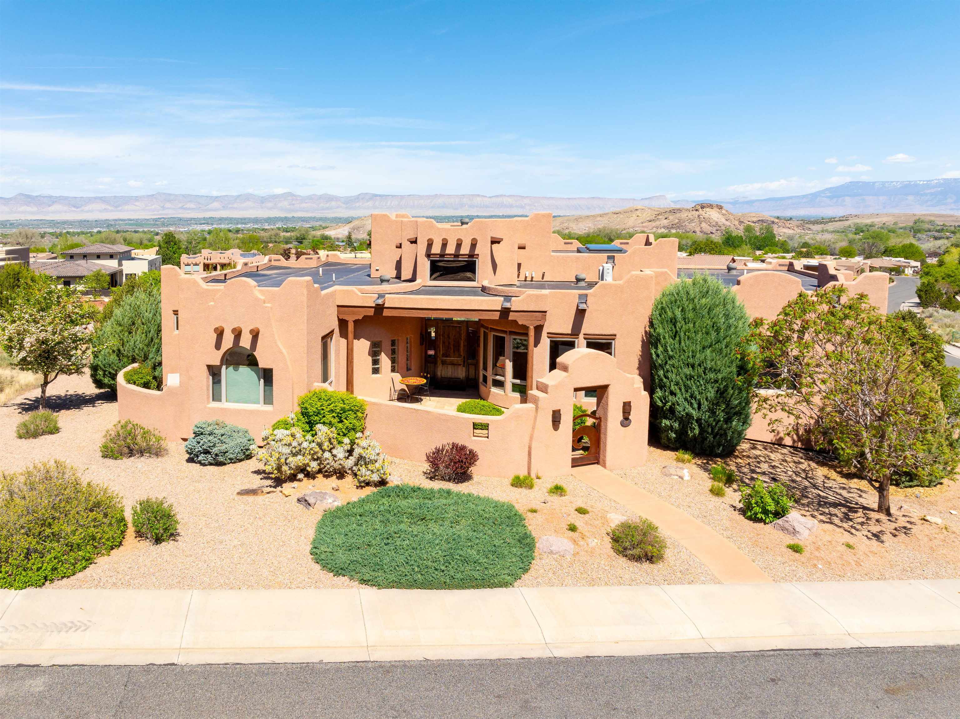 The minute you step in to this truly unique high-desert oasis you'll be wowed by gorgeous views out of every window and stunning detail throughout.  Built by Maves Construction, this Parade of Homes beauty has been carefully throughout, designed and maintained by the original owner/designer.  Featuring two kiva fireplaces, soaring ceilings with vigas and custom, 8 ft knotty alder doors and cabinetry, all bedrooms have an ensuite bath and ample closet space. The gourmet kitchen will please the most discerning of cooks. Wine connoisseurs will appreciate the wine room adjacent to the formal dining space, a great opportunity to take in the Monument view. Outside, you'll find multiple patios, an outdoor kitchen with granite countertops, a stunning water feature and multiple vantage points to take in the best of the Grand Valley landscapes. An elevator ride to the lower level leads to the bonus room, 1/2 bath, oversized 3 car garage and extra storage. This home has been carefully curated and maintained, furnishings are negotiable.  Book your private showing today!