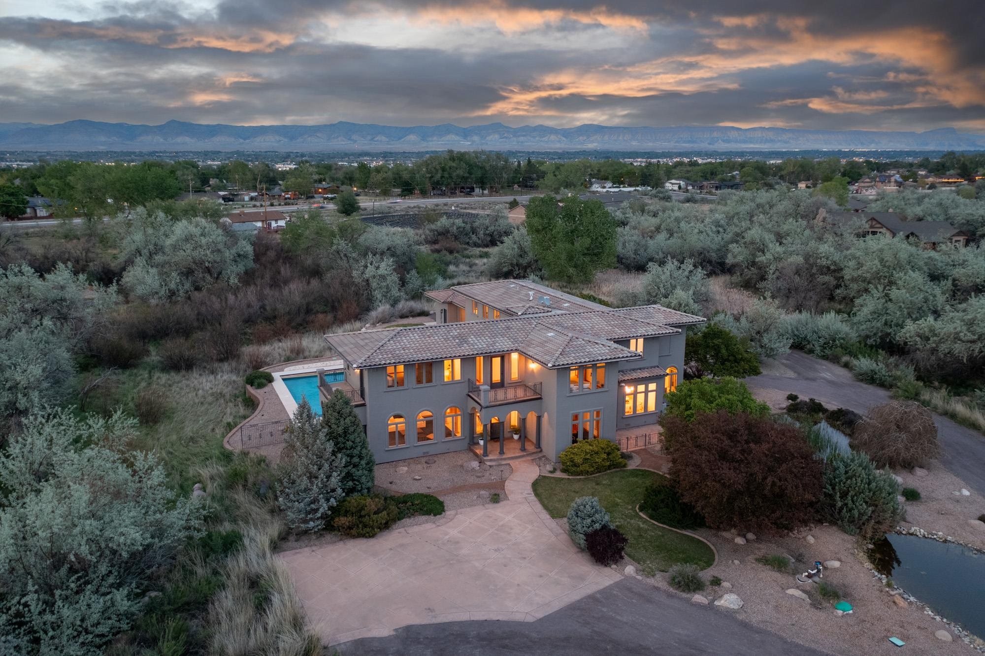 Welcome to Villa Serenita “serene villa” - an 8.36 private sanctuary within a secluded nature preserve in the high desert of Grand Junction, Colorado. This signature estate with detached casita/ADU & salt water pool is positioned near the base of the Colorado National Monument, capturing epic vistas, sunrises and sunsets... memories to be made. The property is located at the very back of the preserve for exceptional quietude and privacy. Several updates have been made to the estate recently, including but not limited to: all new low-E windows & swinging doors, new interior & exterior paint, all new modern fixtures (lights, ceiling fans, faucets, etc), new professional vent hood, modern accent trim in kitchen, refreshed landscaping and more. The detached 430 sqft casita/ADU/pool house is fully-furnished as a 1-bedroom studio (furniture included) and features hand-hewn beams, a stained concrete floor, its own patio overlooking the pool & dedicated 1 car garage. Escape in the sapphire blue 20’x40’ salt water pool featuring a newer liner, cover & heater... imbuing every sense of the word 'vacation'. The theater/game room features a wet bar and includes the pool table, A/V system (TV & sound) and epic views of the Monument & Bookcliffs. The gourmet chef’s kitchen features Kitchen Aid chef-series appliances, hickory cabinets & double-thick granite countertops with chiseled edges. The oversized island is ready to entertain and prepare the most dazzling holiday feasts! The upstairs features the primary retreat wing with French door entry, generously spacious walk-in closet and 5-piece en-suite spa bathroom. The junior primary also features an en-suite bath and its own balcony. Not to miss, extra attention to detail in the custom copper gutters and the Villa Barcelona Serena French Oak heritage wood trim & doors. Walk-in wine cellar, huge walk-in pantry, office with built-in bookcases, breakfast nook with its own patio, and a sunny sitting/dining room with custom copper-finish ceiling and its own shady patio. In addition to the pool patio there are plenty of outdoor living areas, including the two ponds in front and a meadow with a creek behind the casita. The expansive outside patio has gas & water hookups to build your dream outdoor kitchen. Plenty of room to park your RV & toys as well as guest parking. This unbelievable estate is close to schools, shopping, and adventure, and ready for new owners to make it their own. Book your private showing today!