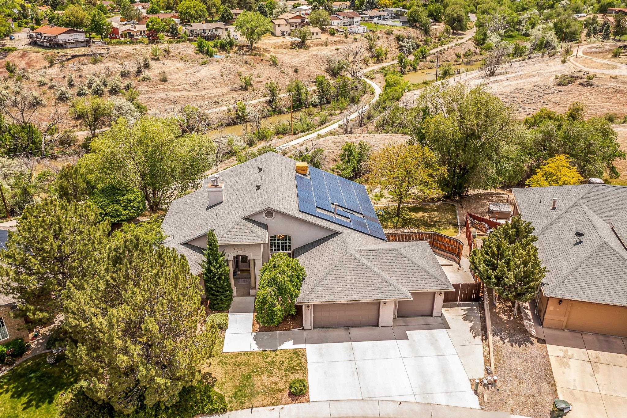 Experience luxury living in the sought-after Redlands South Rim neighborhood. This stunning ranch-style home with a walk-out basement is situated on a spacious half-acre cul-de-sac lot. Enjoy the perfect blend of elegance and comfort, enhanced by owned solar panels that offer eco friendliness and lower utility costs.   Inside you will find a layout designed for relaxation. The main level features a grand primary suite with a cozy fireplace and a balcony with breathtaking views of the Colorado National Monument, Grand Mesa, and Mount Garfield.   The well-equipped kitchen flows seamlessly into multiple living areas and a refined dining space, perfect for gatherings and entertaining. The oversized master suite features a gas fireplace and a jetted tub.  Two bedrooms connected by a jack-and-jill bathroom, include a reading nook and window seats.   The finished walk-out basement includes a large fourth bedroom with a Murphy bed that can mutually serve as a playroom and guest room, just as an extra bedroom. The living area for games and TV or a music room walks out to the patio with the hot tub.   There's also a separate residence with an oversized bedroom, multiple closets, a fully-equipped kitchen, laundry facility, and storage space that is ideal for rental income or extended family.   Outside, enjoy the landscaped grounds with a private patio. A three-car garage and additional parking pad to ensure convenience. Expansive windows showcase the picturesque views and direct access to lakes, trails, and wildlife watching.