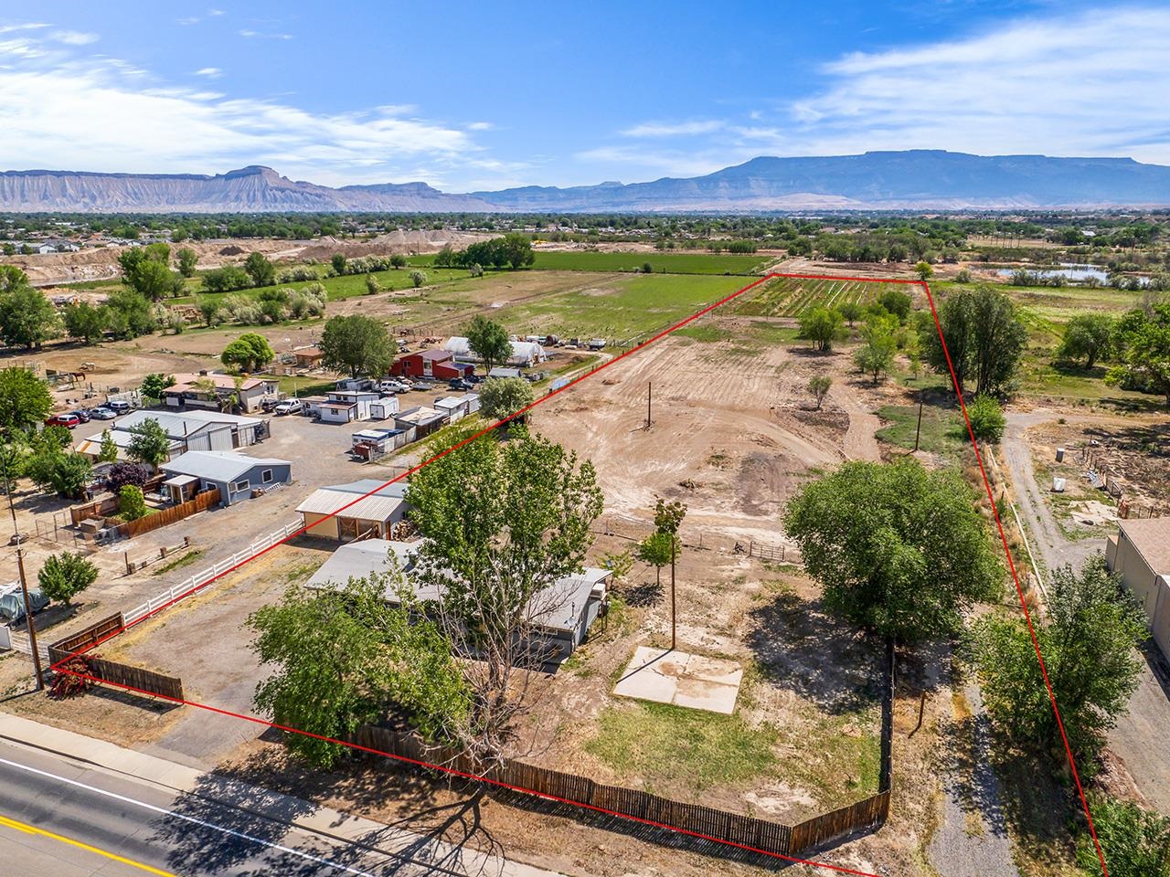 Come see this beautifully remodeled home in Southeast Grand Junction! Situated on 6.43 acres of land, this property offers incredible potential, especially for agricultural uses. Conveniently located near shopping, restaurants, and the Colorado River, you'll find plenty of activities to enjoy. Step through the front door and into a sleek, modern living space lit by the natural light from the double windows. The cozy brick wood-burning fireplace with a built-in mantle adds a charming accent to the room, complemented by contemporary ceiling fans and lighting fixtures. The combination kitchen and dining area is perfect for your inner cook, featuring stainless steel appliances, granite countertops, a sleek kitchen island, and stylish fixtures that create an open and inviting atmosphere for culinary and dining experiences. Just off the kitchen, a well-lit sunroom offers versatile space for any homeowner's needs. The sunroom is accented by a beautiful sliding wooden door for added privacy, and it provides access to a laundry room/half bathroom, as well as the back patio. Down the hall from the living area, you'll find a spacious spare bedroom and a full bathroom adorned with a stunning wooden vanity with a raised bowl sink and a tub/shower combo with an appealing tile backsplash. The warm primary suite has been updated to offer ample space and includes two closets for all your wardrobe needs. This home would be easy to convert back to a 3 bedroom home! Outside, an open back patio provides access to the outbuilding and a fire pit in the yard, perfect for enjoying the outdoors and the unobstructed views of the Grand Mesa. The additional acreage offers endless possibilities for planting, building, raising livestock, or keeping horses. Don't miss this opportunity to own your own slice of acreage with endless possibilities and a beautifully updated modern home. Schedule an appointment today!