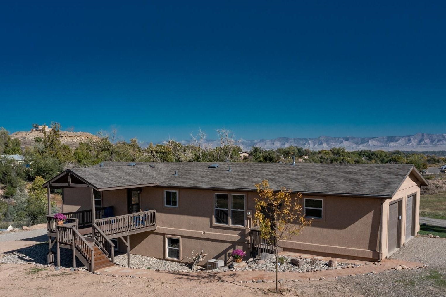 Pending before print. Rare and Amazing Opportunity in Grand Junction, Colorado. Enjoy breathtaking views of the Colorado National Monument, the Mesa, and the Bookcliffs from this 1.29 acre property in the desirable Redlands Area. This beautifully remodeled 5-bedroom, 3-bathroom ranch-style home with a walk-out basement offers incredible versatility. The main level features 3 bedrooms and 2 bathrooms, while the basement includes 2 additional bedrooms, a second kitchen, a spacious living area, a bathroom, and a separate entrance with its own parking. This setup allows you to enjoy the entire home or utilize the basement as an Airbnb or in-law suite. **Buyer to verify any and all rental options. Recent updates include a new roof, new stucco, new Trex deck, new kitchens, new primary suite, new flooring, and updated bathrooms. The home also boasts high-speed internet, an irrigation system, central air, a gas fireplace, RV parking, and city sewer. Additional features include the potential to build an accessory dwelling unit and/or a shop, plus the property allows for horses. The main level is a UBC Factory Built Home, meeting the Universal Building Code which lenders look at it the same as a site built home. The garage and full basement are site built.