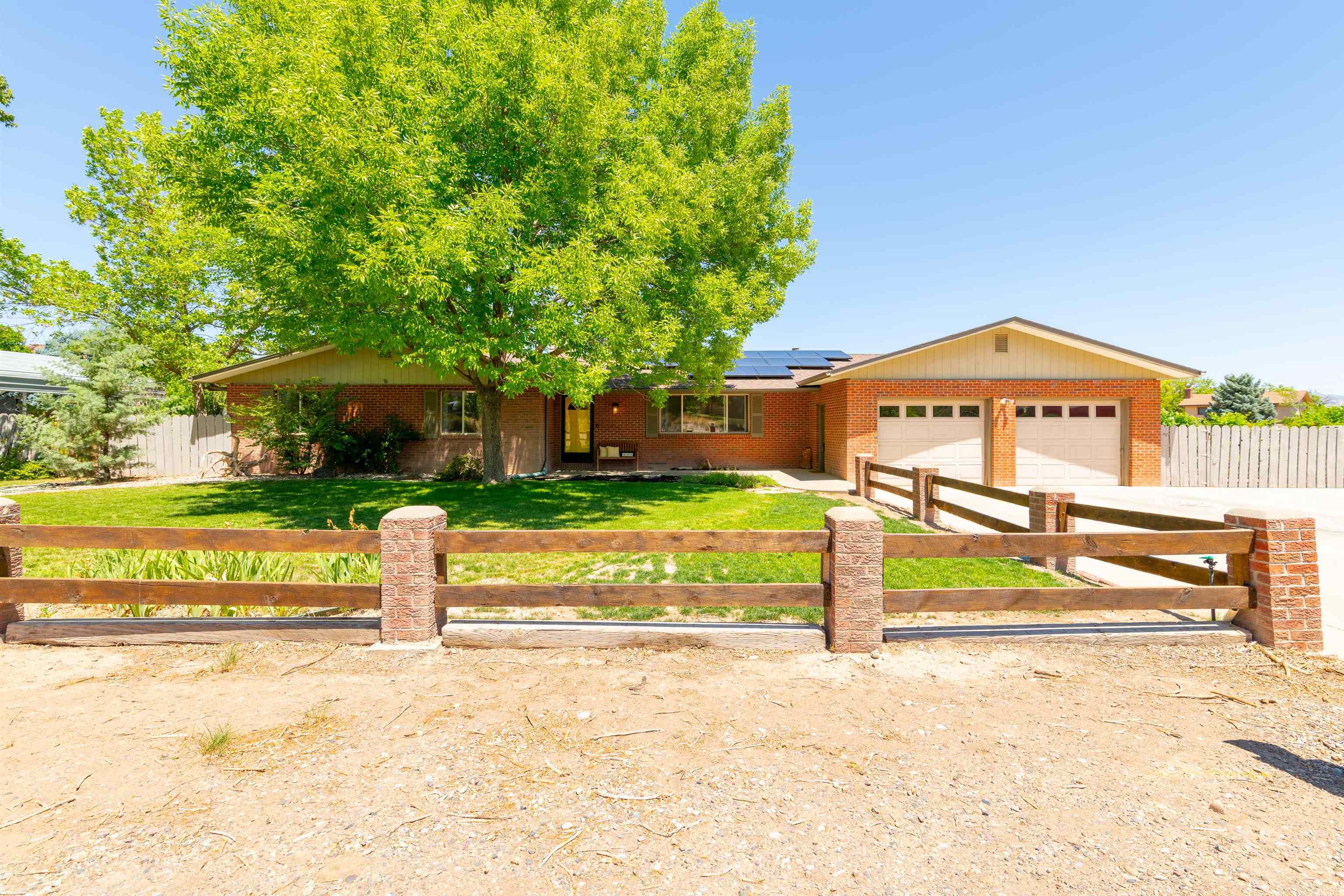 Don't you just love a brick house? This property features established landscaping, ample RV parking, 2 car garage + detached garage/workshop. Several varieties of fruit trees grace the backyard with ample gardening space and a large covered patio make this very useable space. The interior was updated in 2024, new roof in 2022, the solar panels are owned.  Inside you'll find a large kitchen/dining space with tons of storage and counter space, a living room with views of the Monument and family room with cozy brick fireplace.  The bedrooms are roomy, light and bright. Book your private showing today!