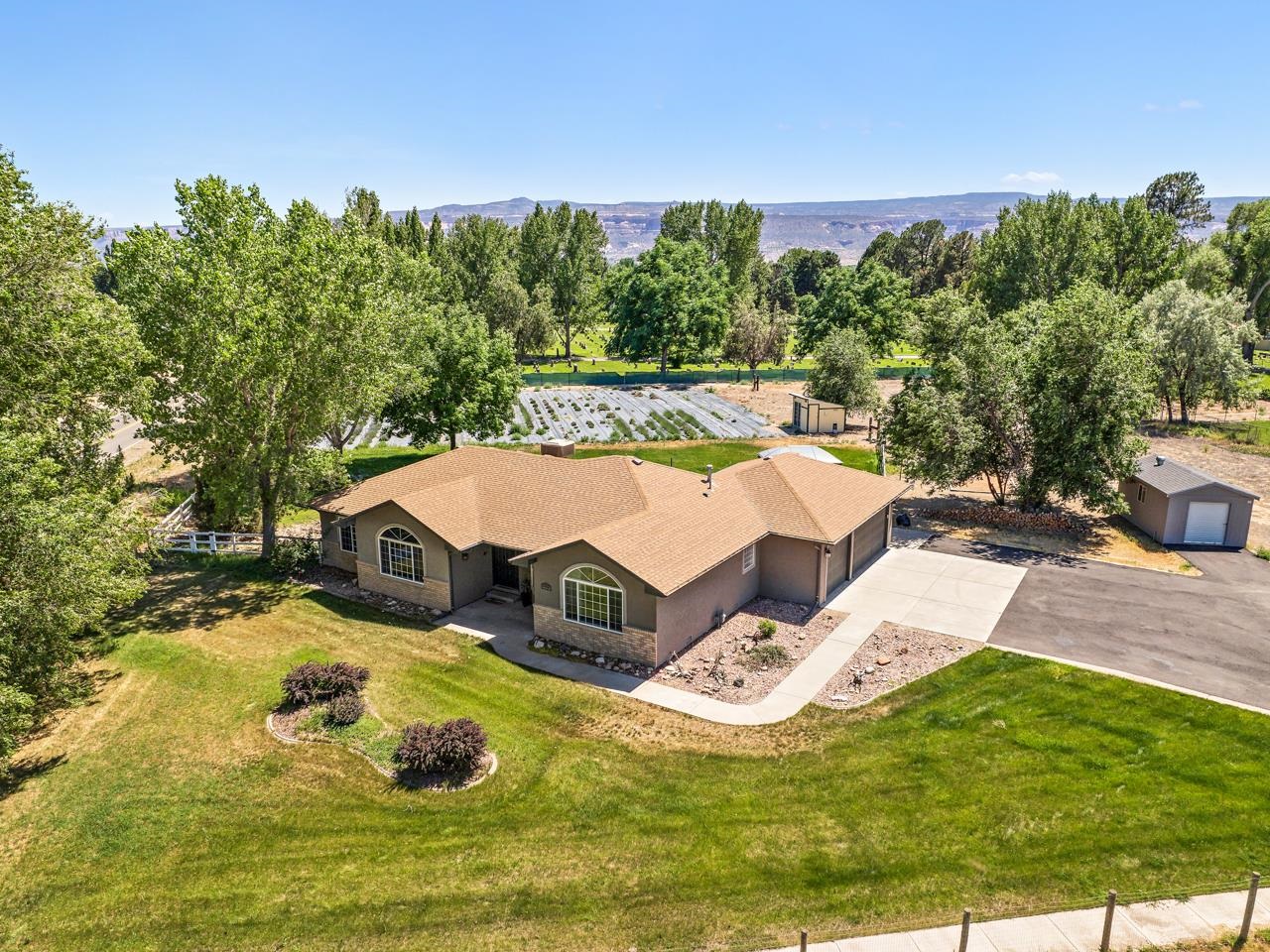 In the north of Fruita, just off K 3/4 Rd, there sits a charming home just waiting for you to make it yours! Set on nearly two acres, this property has a sprawling yard with boundless potential. Step out back, and discover a large, and I mean LARGE, garden laid out for effortless irrigation, offering loads of space to cultivate your favorite plants and vegetables. The panoramic views are a standout feature, with the majestic Colorado National Monument to the west and the beautiful Bookcliffs to the north, creating quite the backdrop to every angle. Now let’s step inside. Experience the modern comforts and spaciousness of this inviting home. Upon entry, the airy open floor plan welcomes you with vaulted ceilings and beautiful luxury vinyl planking. An inviting informal dining area makes for the perfect spot to host gatherings and enjoy meals. To the right, a versatile living space with French doors awaits, adaptable for use however you’d like. Imagine it as a home office, studio, or even a non-conforming bedroom (giving it AirBnB potential). The kitchen features stainless steel appliances, sleek granite countertops, and contemporary cabinetry, seamlessly blending style with functionality, not to mention the easy flow around the central island that will make getting meals ready a cinch. The living area has tons of warmth and natural light, complemented by a large window that frames the view perfectly. Down the hall, discover additional bedrooms and a full bath, each offering comfort and privacy. The primary suite is a full retreat unto itself, offering lots of space and views through the large front facing window. A spacious walk-in closet provides extra storage for your garments, while the en-suite bathroom features a stylish modern design sink and a luxurious walk-in shower with dual heads. Outside, the big open back patio is ideal for outdoor entertaining and relaxation, complete with a fire pit, seating area, and a built-in canopy a great spot to unwind and enjoy the serene surroundings. Space for RV parking is readily available out front to welcome your adventurous side. Located just a short drive from Fruita, this home offers the perfect blend of convenience and suburban peaceful living. Don’t miss out on this opportunity to make this exceptional property your own. Schedule your showing today!