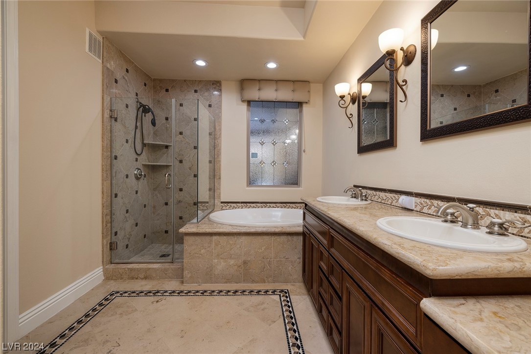 Primary bathroom with dual vanities and makeup area, separate shower and tub