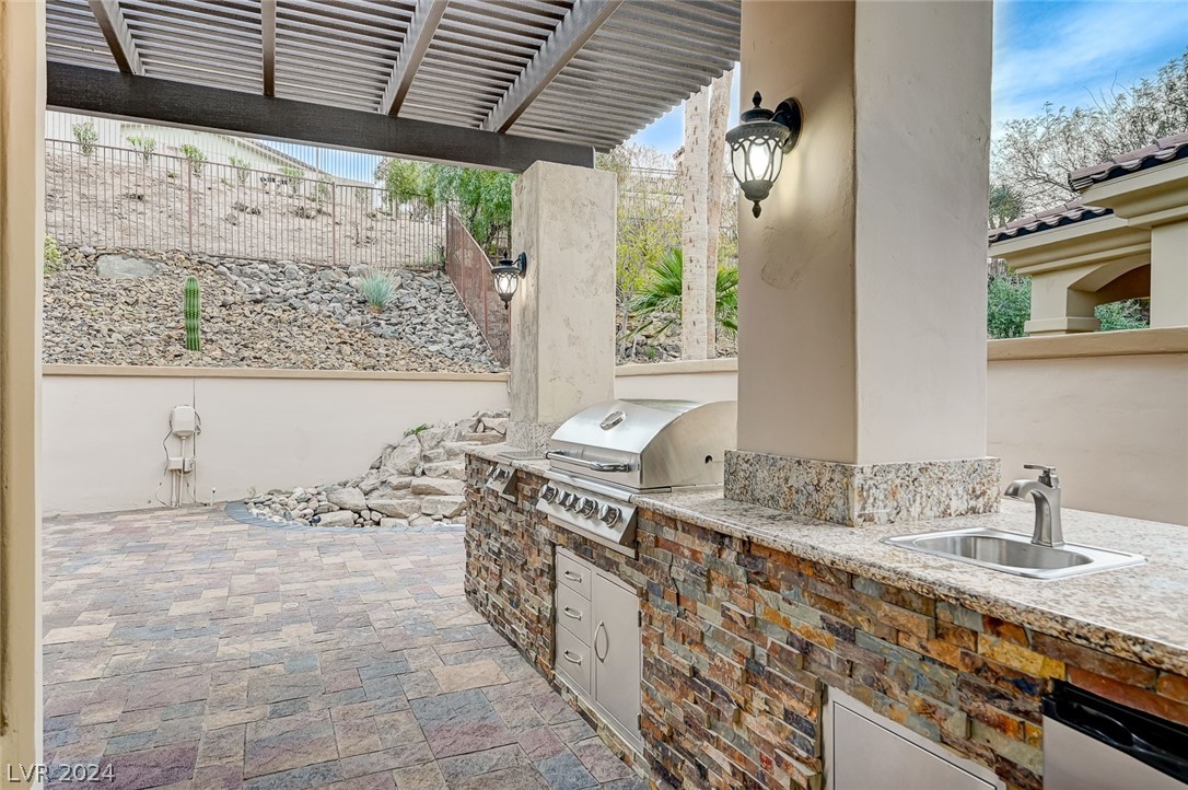 Recently added outdoor kitchen with stainless steel gas grill, stovetop, refrigerator, and sink is excellent for outdoor entertaining under the pergola.