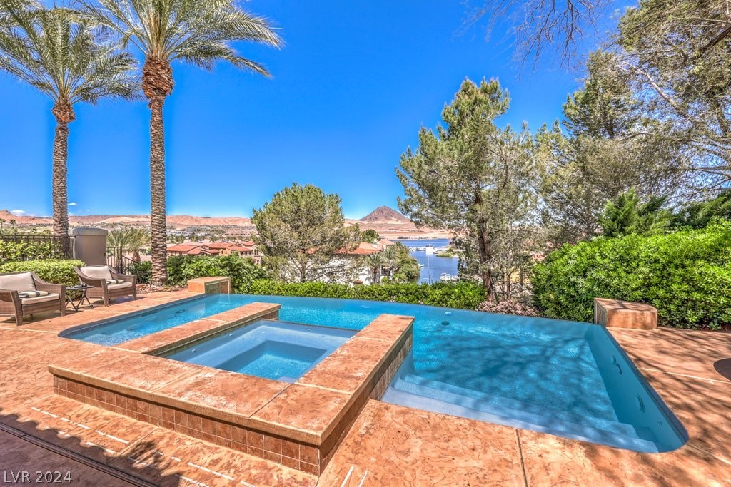 Prepare to be amazed by the views at this single-story home in the highly coveted community of South Shore at Lake Las Vegas. The home features four bedrooms, each with its own private bathroom.  Perched on the hillside, the breathtaking views feature the lake, mountains, and eastern marina. A remodel created a more open floor plan. The oversized primary bedroom has convenient access to the infinity pool and spa. The large lot and backyard include a built-in barbeque, fridge, covered patio area, & space for entertaining. The attached casita holds bedroom and bathroom #4.   A den with French doors offers a space for conducting work. A two-way fireplace accents the family room and formal dining area. The kitchen has an oversized prep and seating island, with the gas cooktop built in. Granite counter tops create a classic look that compliments the paint scheme and window treatments. The built-in JennAir refrigerator, wet bar, wine fridge and ample storage round out the kitchen features.