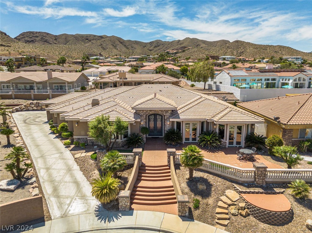 Be amazed by the Lake Mead View Estates! With its sweeping gracefulness and opulence, it is unsurprising that the interior of the house was envisioned by the same genius who also designed the iconic Venetian Hotel & Casino.
As you enter through the grand 10-foot front doors, prepare to be captivated by the sheer elegance of this custom masterpiece. This modern Tuscany-style residence features an open floor plan, raised ceilings, and ornate columns creating a space that combines both artistry and hospitality. The chef’s kitchen, wine room, and master suite add perfect touches of class and sophistication. And when its time for leisure, this 4,753 square foot home is perfect: boasting a 411 square foot game room, sparkling swimming pool, and even a relaxing spa.  Complimented with its sweeping lake and mountain landscape outdoors, every element was meticulously planned to create a luxurious experience within this residence. Ready to make it yours?