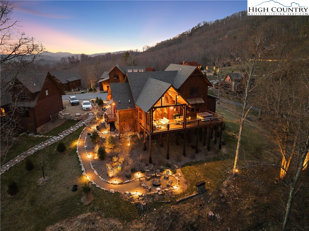 This custom built mountain retreat is located in the maintenance free Village inside the highly desired Lodges at Eagles Nest.  Nestled against the backdrop of majestic Grandfather Mountain, the home promises awe inspiring views. This meticulously crafted mountain retreat is a testament to rustic elegance with hardwood floors throughout, large glass sliders, laurel railing, tongue and groove cathedral ceiling and open concept living area.  The spacious living area seamlessly connects with the kitchen and dining spaces.  The centerpiece of the great room is the floor-to-ceiling stone and barn wood fireplace, adding warmth and charm. Equipped with modern conveniences the kitchen includes the oversized island, wine cooler, prep sink, barn wood accents and stainless steel appliances. The mudroom/laundry has access on the side of the home and features an additional pantry area, and custom built cabinetry. The primary suite is located on the first level and features a luxurious en suite bath with walk-in in shower  and custom vanity area. The loft game room is a haven for entertainment enthusiasts! Gorgeous vaulted tongue and groove ceilings, and large barnwood sliding doors add rustic charm while the large glass windows expose the beautiful layered Grandfather mountain views. Large additional storage room located in the fame room. The guest-room bunk room beckons with custom-built bunk beds for four, each nook adorned with individual reading lights. Additional guest-room and beautifully appointed guest bath also located upstairs. Your outdoor oasis awaits! Step onto the expanded covered porch with stone fireplace, multiple seating areas, gas hookup for grill and hot tub!  Venture down to the firepit, this outdoor haven is your escape to serenity. Additional features include upgraded landscaping, gutters, electric blinds in master, landscape lighting, ATV garage with concrete flooring and oversized parking area.
