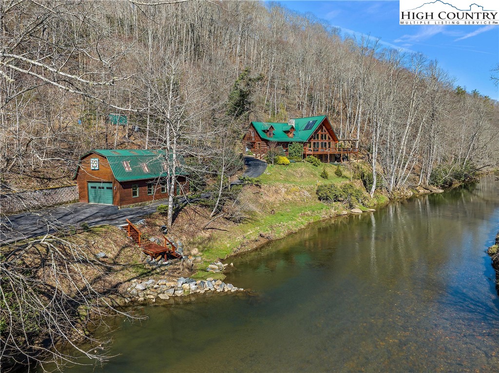 Treat Yourself to this beautiful Mountain Home on the New River, Very rare and fantastic offering just outside Boone NC,  450+ feet on the New River with excellent year round access for fishing, kayaking, and all the water sports. This home is a true Mountain lodge for your family to gather and celebrate here, over 4000 rustic feet await you with outdoor living space also, bubbling hot tub, the outdoor fireplace is a feature with a pizza oven, yes, a pizza oven, covered and uncovered decking to relax an enjoy the views of the river as it flows by. 3 bedrooms 2.5 baths, Master on the main level with a Fireplace,   Fireplace in the downstairs guest suite,  The Mountain side is covered with flowers and plantings that are about to pop out and be beautiful for 7 months of the year. Swim and Fish in your slice of Heaven, warm yourself by the fireplace in the Master bedroom or the Living Room or the guest suite downstairs....pick your fireplace...Catch your mountain home on the New River,.... Wow....don't hesitate to come and see this beauty.