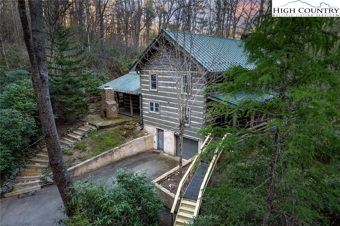 Rare opportunity for the avid fly fisherman and lover of the great outdoors to own a custom-built log home on 3.79 acres with 575-plus feet of Howards Creek frontage, only minutes from Boone, ASU, and other amenities. Cross the rushing creek and follow the driveway to your new home nestled in the woods. Custom-built by a father-son team with hand-hewn hemlock logs shipped from Canada and handsome interior walls of local wormy chestnut, cherry, and knotty alder. The main floor has a comfortable living room with a rock fireplace and gas logs, a half bath, a laundry room with its own entrance out to the back covered porch and patio, a spacious gathering room with a kitchen and ample dining space, and a primary en-suite bedroom with a full bath and exterior door to outdoor fireplace and patio. The second floor has two large bedrooms and a shared full bath plus a cozy office/playroom. A sweeping front porch offers a view of the rushing creek and a quiet space for relaxing. The lower level has garage parking, a workshop area, and lots of storage space. The seller receives mail at the downtown Boone Post Office. No physical mail delivery is available at this time.