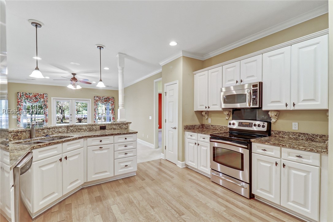 Kitchen featuring ceiling fan, light hardwood / wood-style floors, sink, stainless steel appliances, and white cabinets