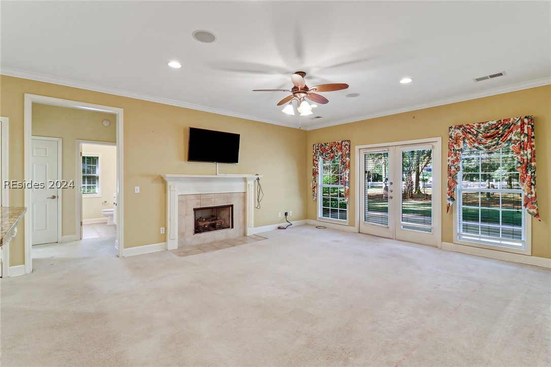 living room featuring a healthy amount of sunlight, light colored carpet, and a tiled fireplace
