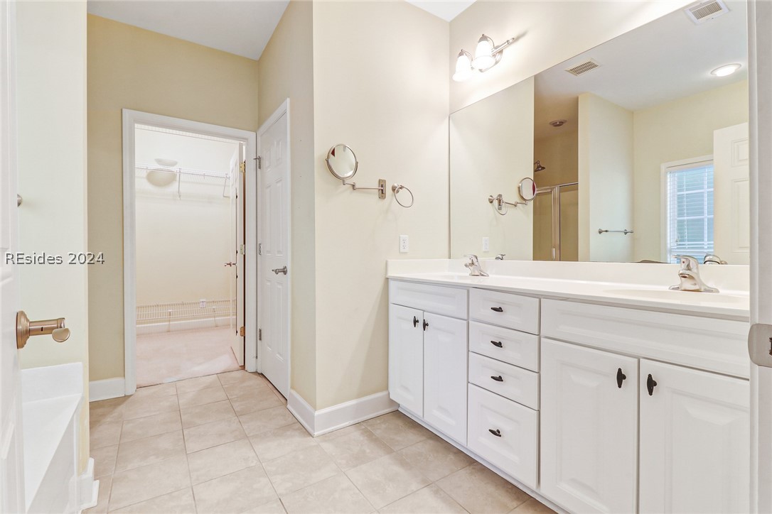 Bathroom featuring vanity with extensive cabinet space, tile flooring, double sink, and a bathing tub