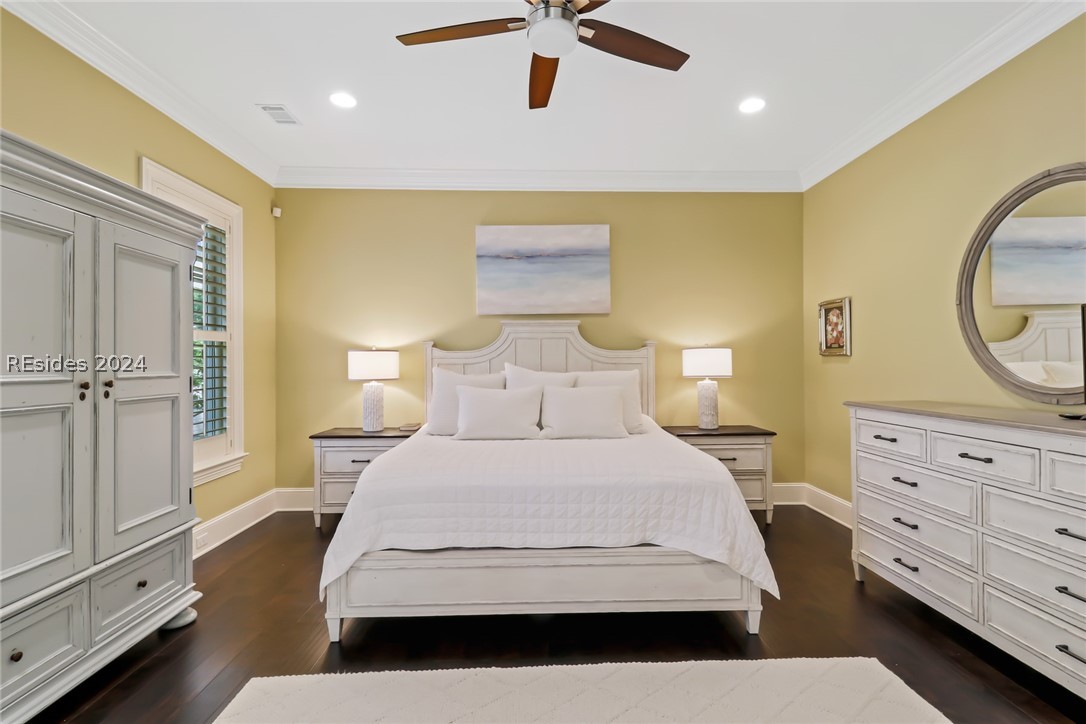 Primary Bedroom with ceiling fan, ornamental molding, and dark hardwood / wood-style floors