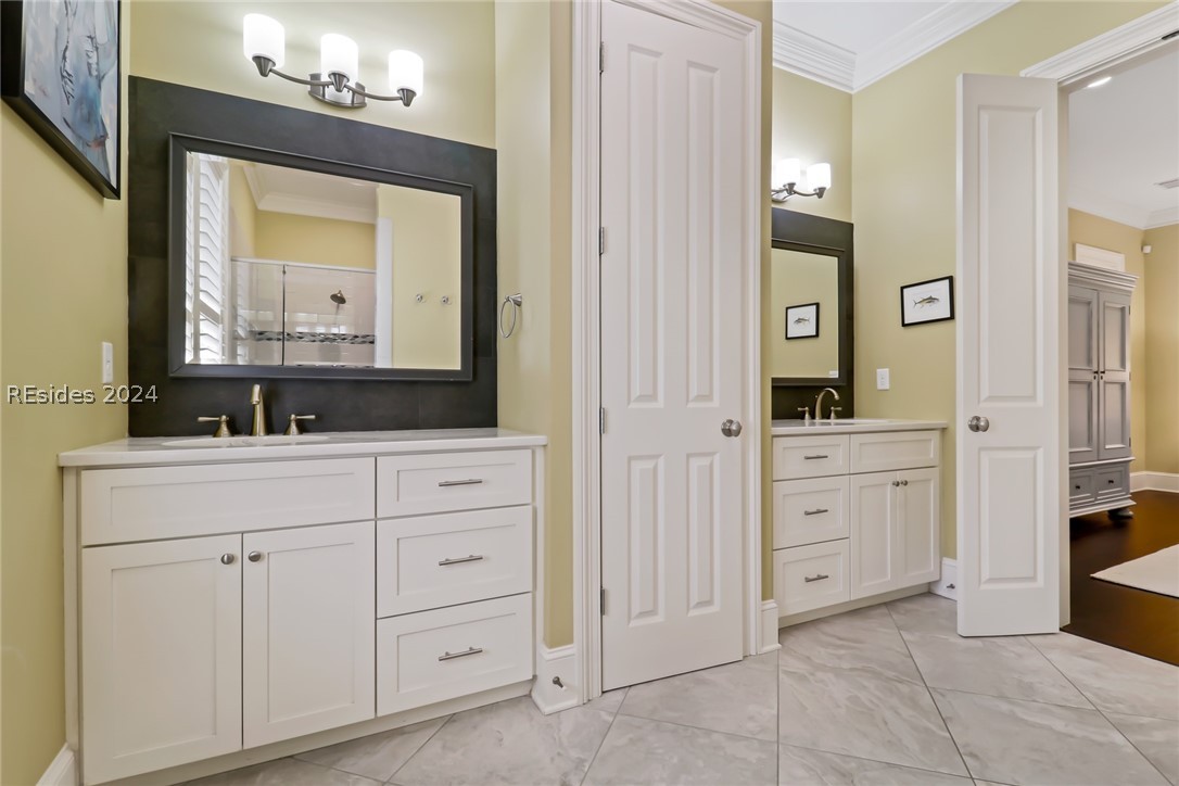 Bathroom featuring tile floors, ornamental molding, and dual vanities