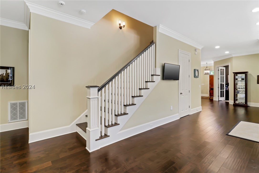Staircase with crown molding and dark hardwood / wood-style flooring