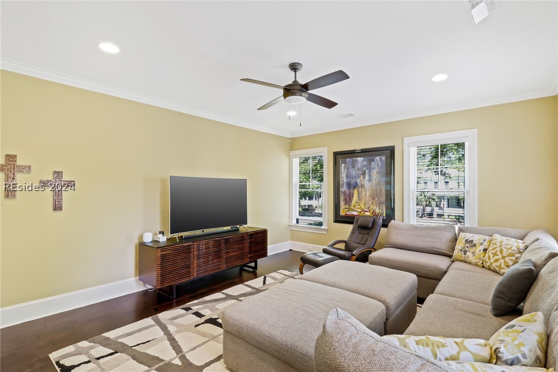 Living room featuring crown molding, dark hardwood / wood-style floors, ceiling fan, and a wealth of natural light