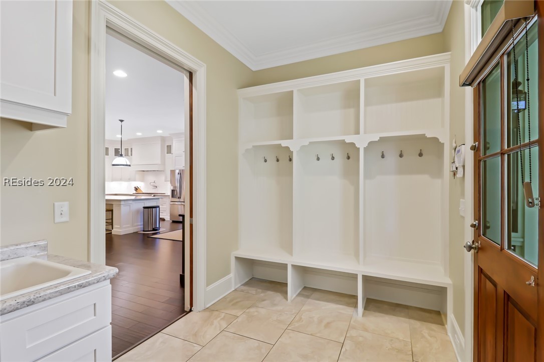 Mudroom with crown molding, sink with marble counters, and light hardwood / wood-style flooring