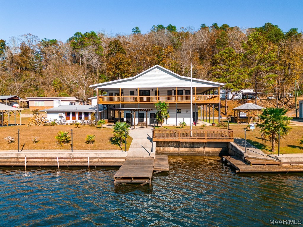 Custom built lake home with a flat lot and 178 ft. +/- of waterfront.  The main home was built in 2004 and the original cabin was remodeled at that time.  Inside you have 3 bedrooms, 2 baths, 2 kitchens, and 2 dens.  If you are looking for a vacation rental, you can easily separate this home into 2 living areas.  Upstairs you have a wrap-around porch overlooking your dedicated swimming area.  Downstairs you have a full bath and an outside kitchen located lakeside.  There are 2 gazebos to choose from.  One has a built-in grill.  You have a 60 x 38 metal building with 4 garage spaces for your water toys and extra vehicles.  Lakeside you have a poured concrete seawall, boat ramp along with a covered fish cleaning station with fish basket and winch.  There is plenty of parking for family and friends plus and RV hook-up.  Call now for your private showing.