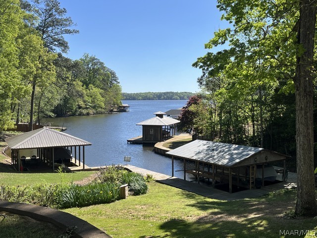 Incredible waterfront home on Holtville side of beautiful Lake Jordan! This masterpiece is the best priced waterfront home per square foot and sits on a huge 2.14 +/- acre parcel with space for future construction, even a pool, and plenty of space for kids, animals, and special toys. The waterfront improvements include a one-slip boathouse w/lift, lovely dock area to entertain, a low maintenance seawall, and a walking boardwalk that goes along the entire slew. This sprawling home features underground utilities, a new roof, new LVP flooring, new tile shower and new tile at tub in master bath, new tile backsplash in the kitchen, and new exterior paint. The great room boasts a 22 ft. volume ceiling, includes custom built-ins, and offers incredible views. It exits to a massive 12 x 52 enclosed porch that makes entertaining a cinch! The kitchen is a chef’s dream with its double ovens, gas cooktop, walk-in pantry, huge island w/service sink & overhead pot hanger, tons of cabinets and granite counter space, and one of the biggest breakfast bars ever seen! The master suite is located on the main level and is absolutely huge and offers great views! The master bath has a new tiled bath and sep shower along with a relaxing jetted tub. You will find a second great room downstairs as well as guest bedrooms, full bath, a gigantic storage room, and a home theater. The downstairs outdoor porch is just as large as the upstairs indoor porch and includes gorgeous slate tile flooring. This marvel of a home is built to last with 15 inch poured walls and a Generac back-up generator that runs the entire main floor plus the theater room. There are 2 tankless water heaters, sec system, added metal awning over side porch, a fenced pet area, and an electric RV hookup. This is truly an incredible home with a lot to offer! Call today to schedule your private tour!!