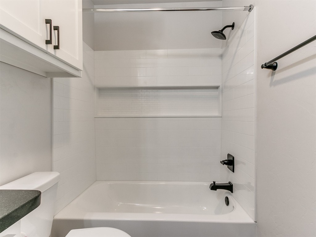 6604 NW 155th Street, Edmond, OK 73013 bathroom featuring tiled shower / bath combo and toilet