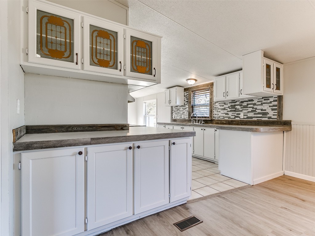 12677 NE 63rd Street, Spencer, OK 73084 kitchen with white cabinets, light hardwood / wood-style flooring, and tasteful backsplash