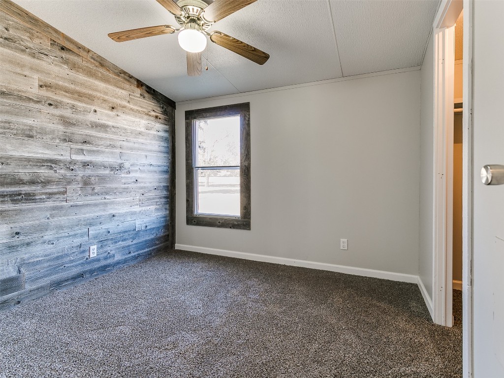 12677 NE 63rd Street, Spencer, OK 73084 carpeted spare room featuring wooden walls, ceiling fan, a textured ceiling, and lofted ceiling