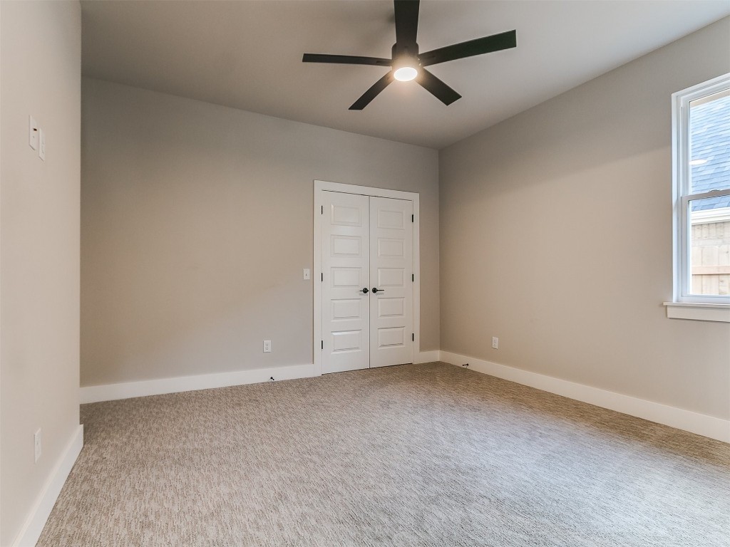 3032 Hunter Crest Drive, Edmond, OK 73034 unfurnished bedroom featuring multiple windows, light carpet, a closet, and ceiling fan