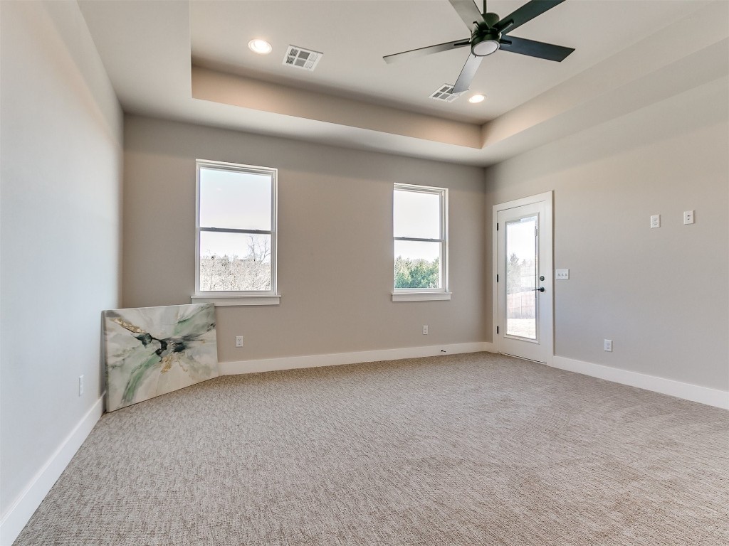 3032 Hunter Crest Drive, Edmond, OK 73034 carpeted empty room with a tray ceiling and ceiling fan