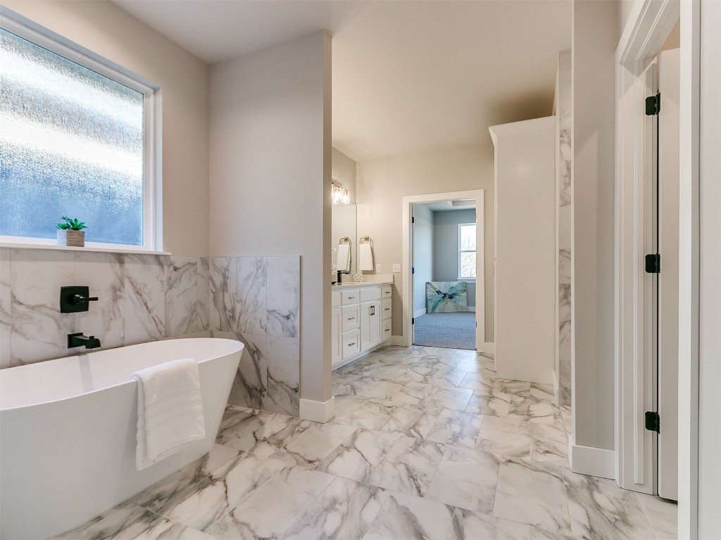 3032 Hunter Crest Drive, Edmond, OK 73034 bathroom featuring tile floors, vanity, a tub, and tile walls