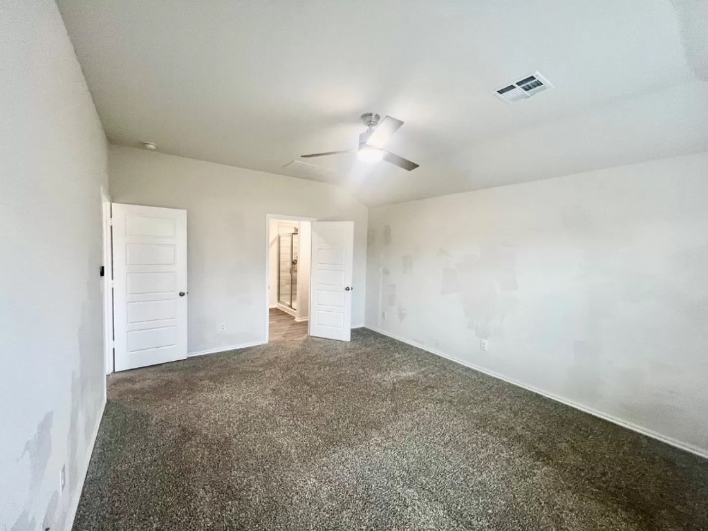 11217 SW 33rd Terrace, Yukon, OK 73099 unfurnished bedroom with dark colored carpet, ceiling fan, and lofted ceiling