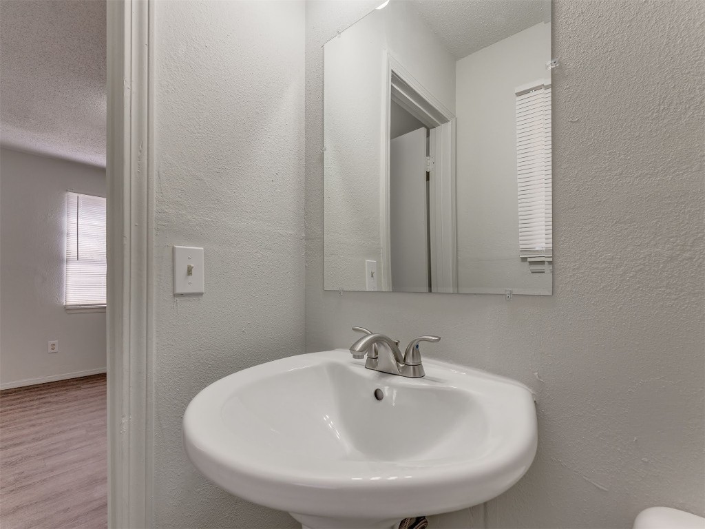 209 NW 80th Street, Oklahoma City, OK 73114 bathroom with wood-type flooring, a textured ceiling, and sink