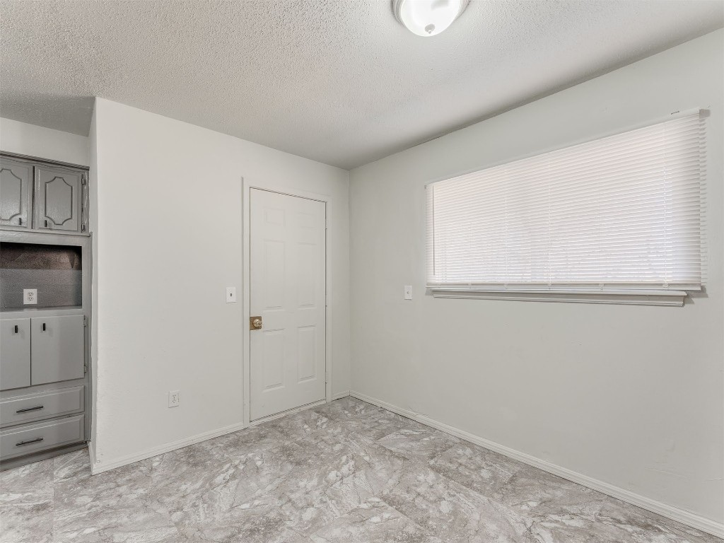 209 NW 80th Street, Oklahoma City, OK 73114 unfurnished bedroom featuring light tile flooring and a textured ceiling