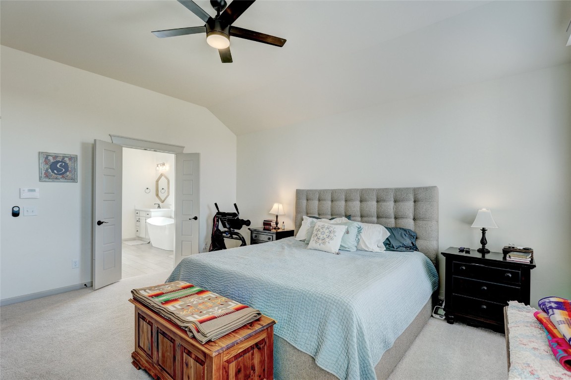 3104 Venice Court, Norman, OK 73071 bedroom featuring ensuite bath, lofted ceiling, light carpet, and ceiling fan