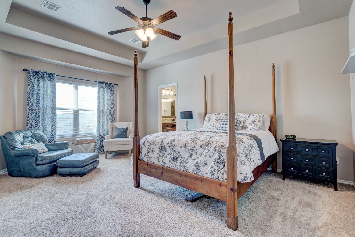 145 Oakridge Drive, Choctaw, OK 73020 carpeted bedroom with ceiling fan, a raised ceiling, and ensuite bathroom