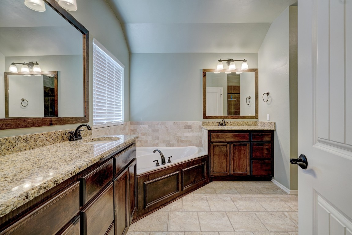 145 Oakridge Drive, Choctaw, OK 73020 bathroom featuring a bathtub, vaulted ceiling, tile flooring, and oversized vanity