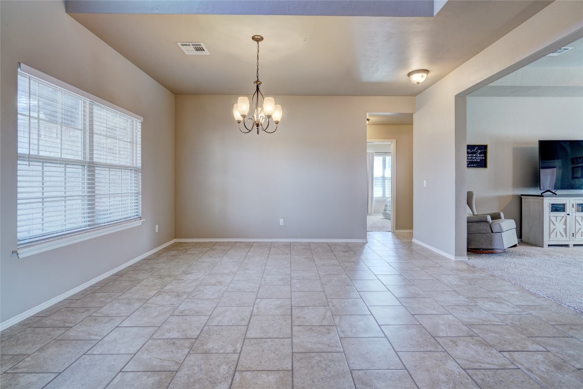145 Oakridge Drive, Choctaw, OK 73020 empty room featuring an inviting chandelier and light tile floors