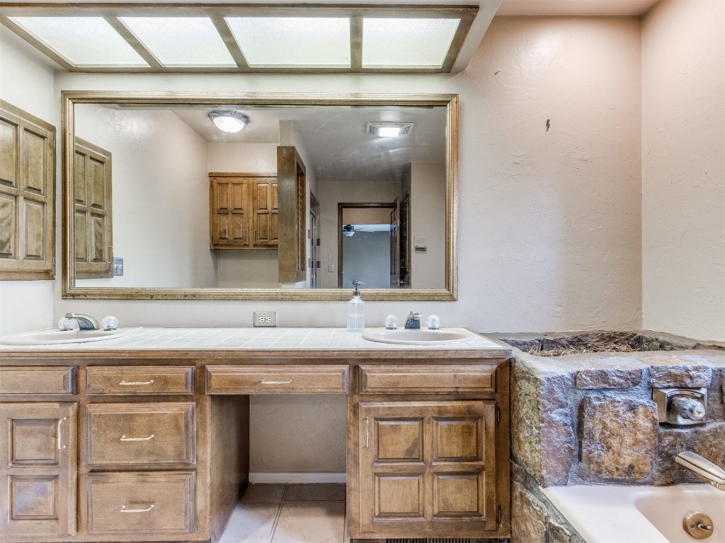 10717 Woodridden, Oklahoma City, OK 73170 bathroom featuring double sink vanity, tile floors, and a bathing tub
