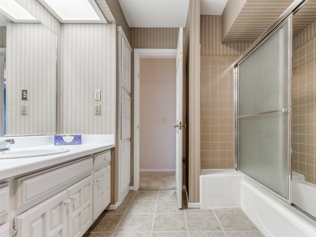 10717 Woodridden, Oklahoma City, OK 73170 bathroom featuring tile floors, a skylight, bath / shower combo with glass door, and vanity