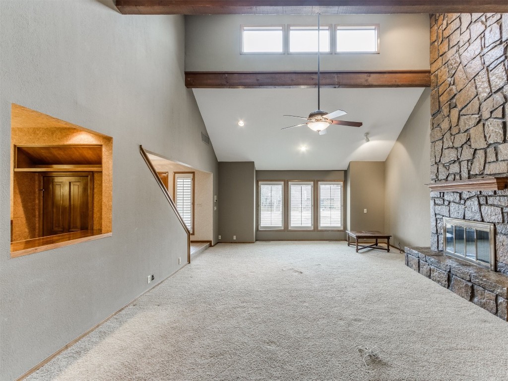 10717 Woodridden, Oklahoma City, OK 73170 unfurnished living room with beam ceiling, a fireplace, ceiling fan, and light colored carpet