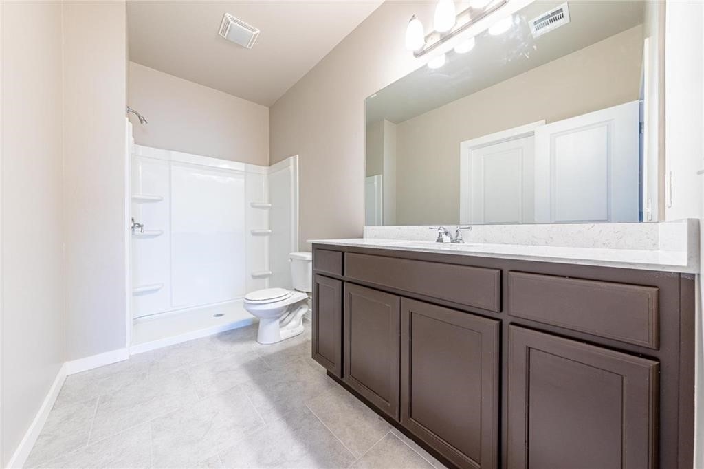 5231 Bluestem Avenue, Guthrie, OK 73044 bathroom featuring vanity, a shower, tile floors, and toilet