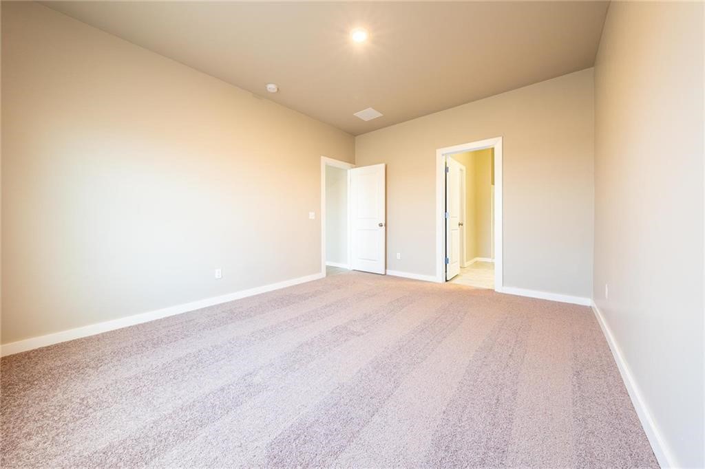 5231 Bluestem Avenue, Guthrie, OK 73044 unfurnished bedroom featuring light colored carpet and ensuite bathroom