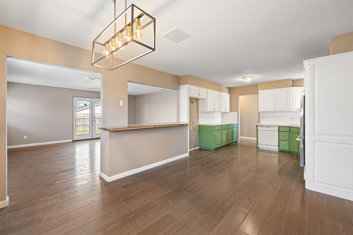 1813 NE 53rd Street, Oklahoma City, OK 73111 kitchen featuring dark hardwood / wood-style flooring, white dishwasher, white cabinetry, green cabinets, and backsplash
