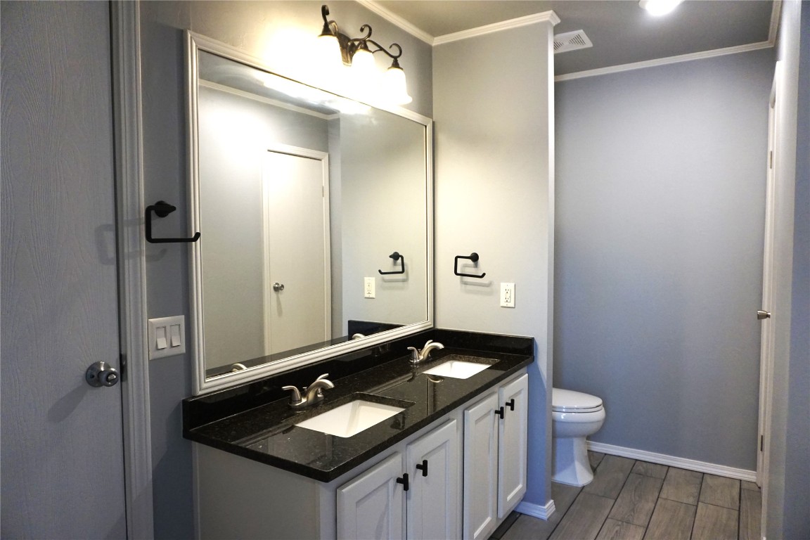 9201 Meadowbrook Lane, Guthrie, OK 73044 bathroom featuring wood-type flooring, dual bowl vanity, ornamental molding, and toilet