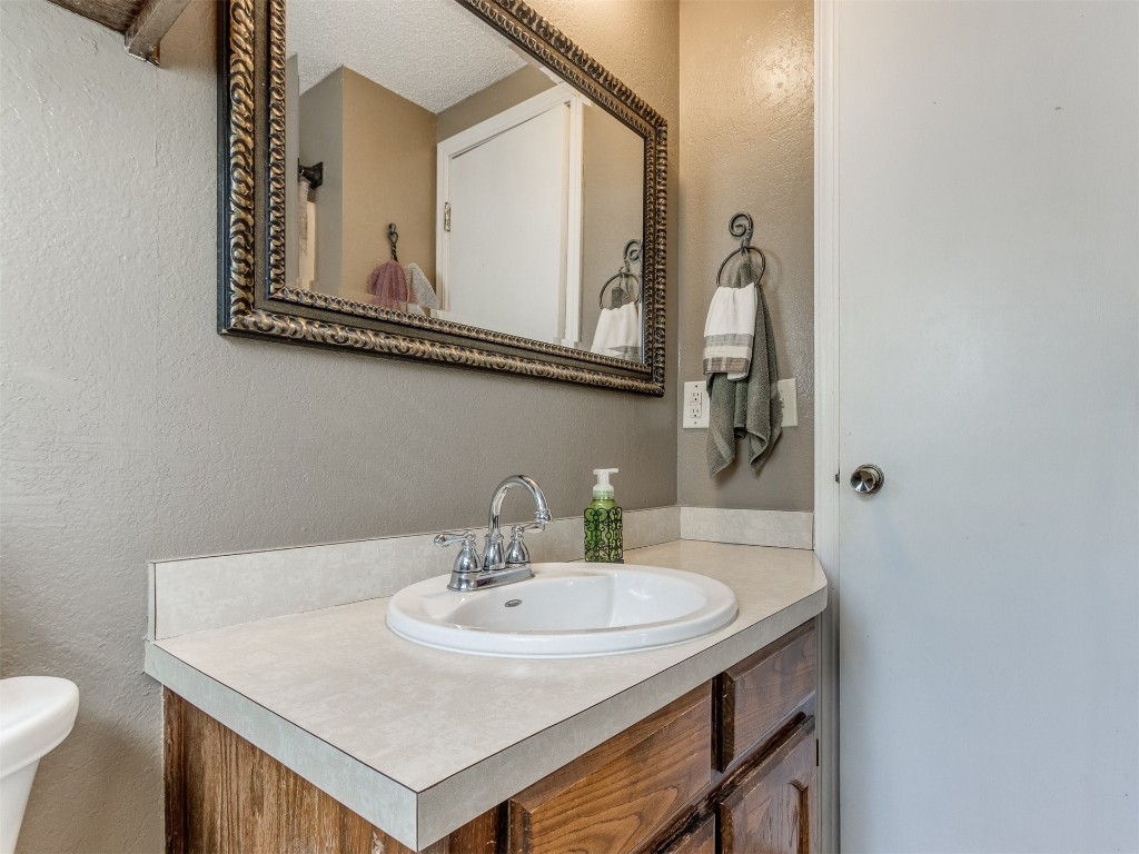 1113 SW 101st Street, Oklahoma City, OK 73139 bathroom featuring toilet, vanity with extensive cabinet space, and a textured ceiling
