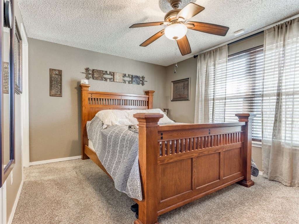 1113 SW 101st Street, Oklahoma City, OK 73139 bedroom featuring light carpet, a textured ceiling, and ceiling fan